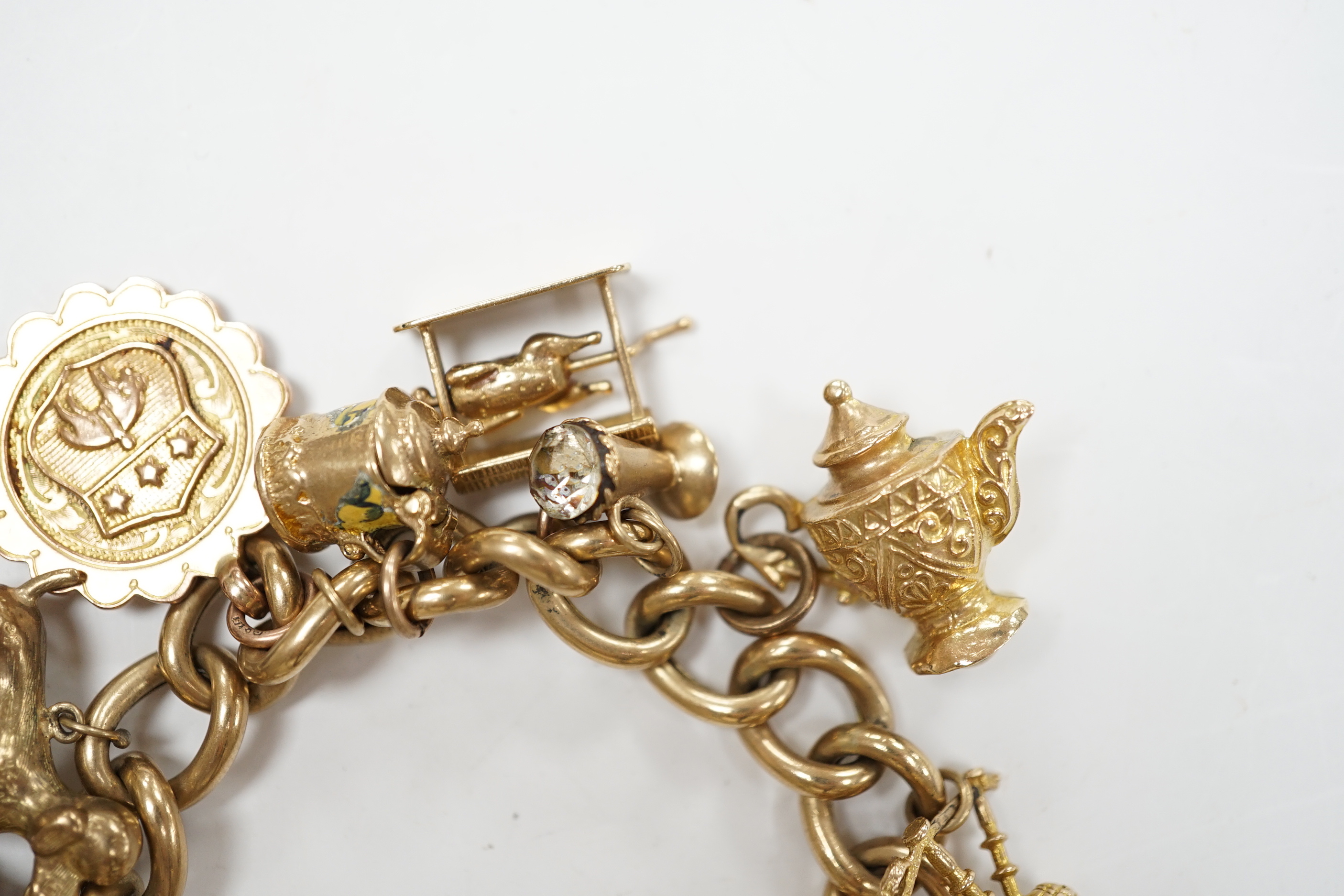 An early 1960's 9ct gold curb link charm bracelet, hung with fifteen assorted charms, including twelve 9ct gold, gross weight 49.7 grams.